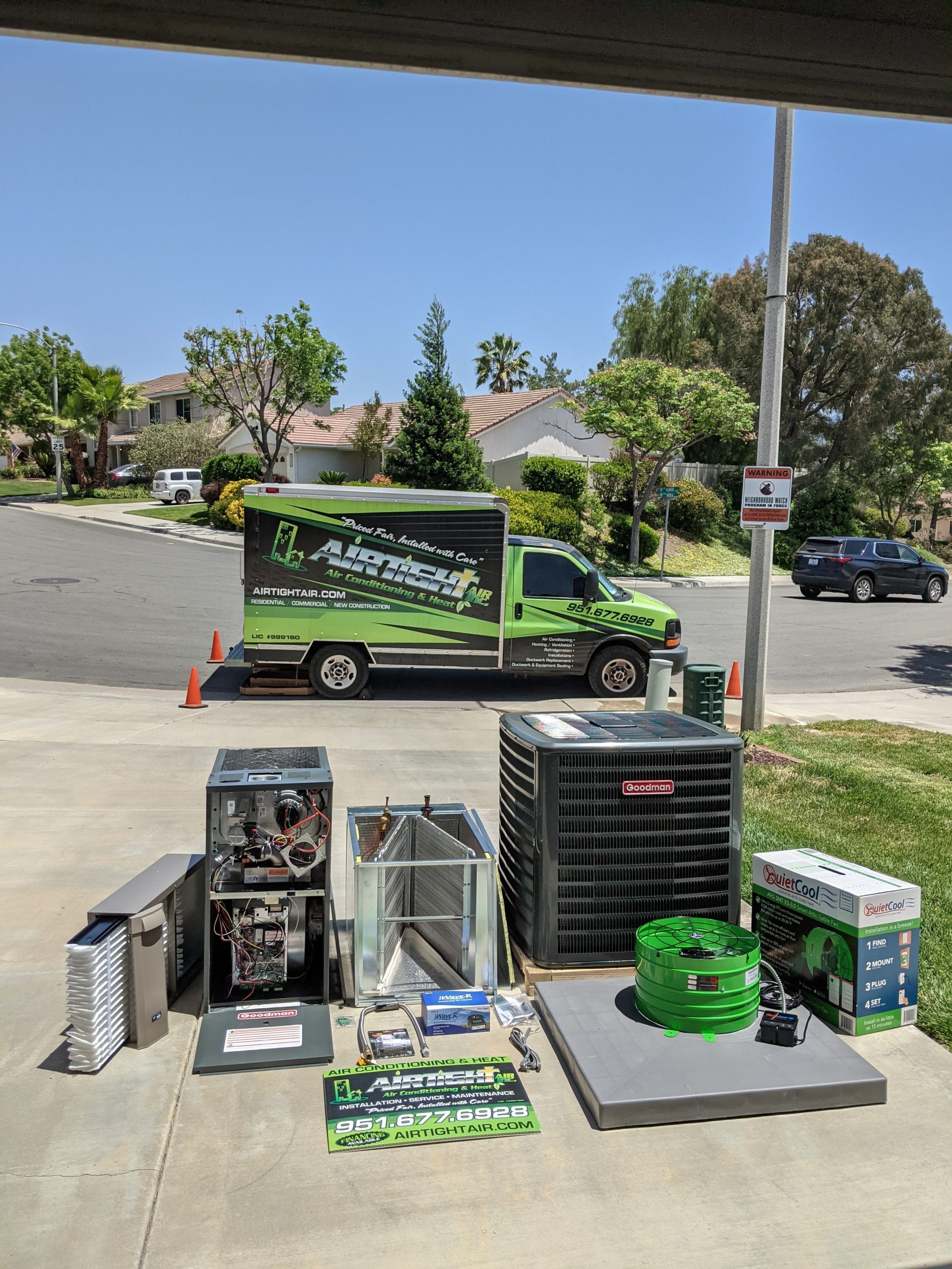An HVAC truck parked outside a residential home with an AC unit and related machinery laid out on the driveway