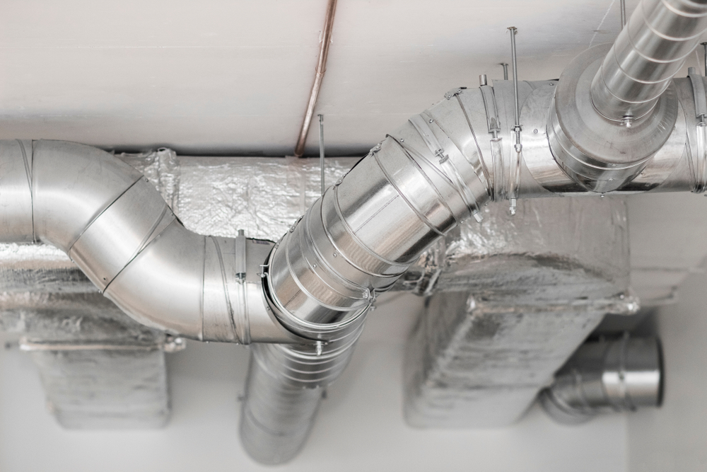 A series of silver ducts near the ceiling of a room